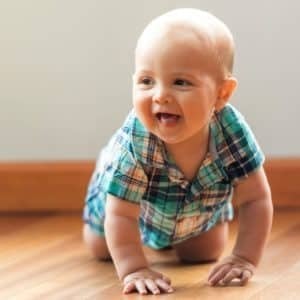 baby wearing plaid shirt crawling on hardwood floor